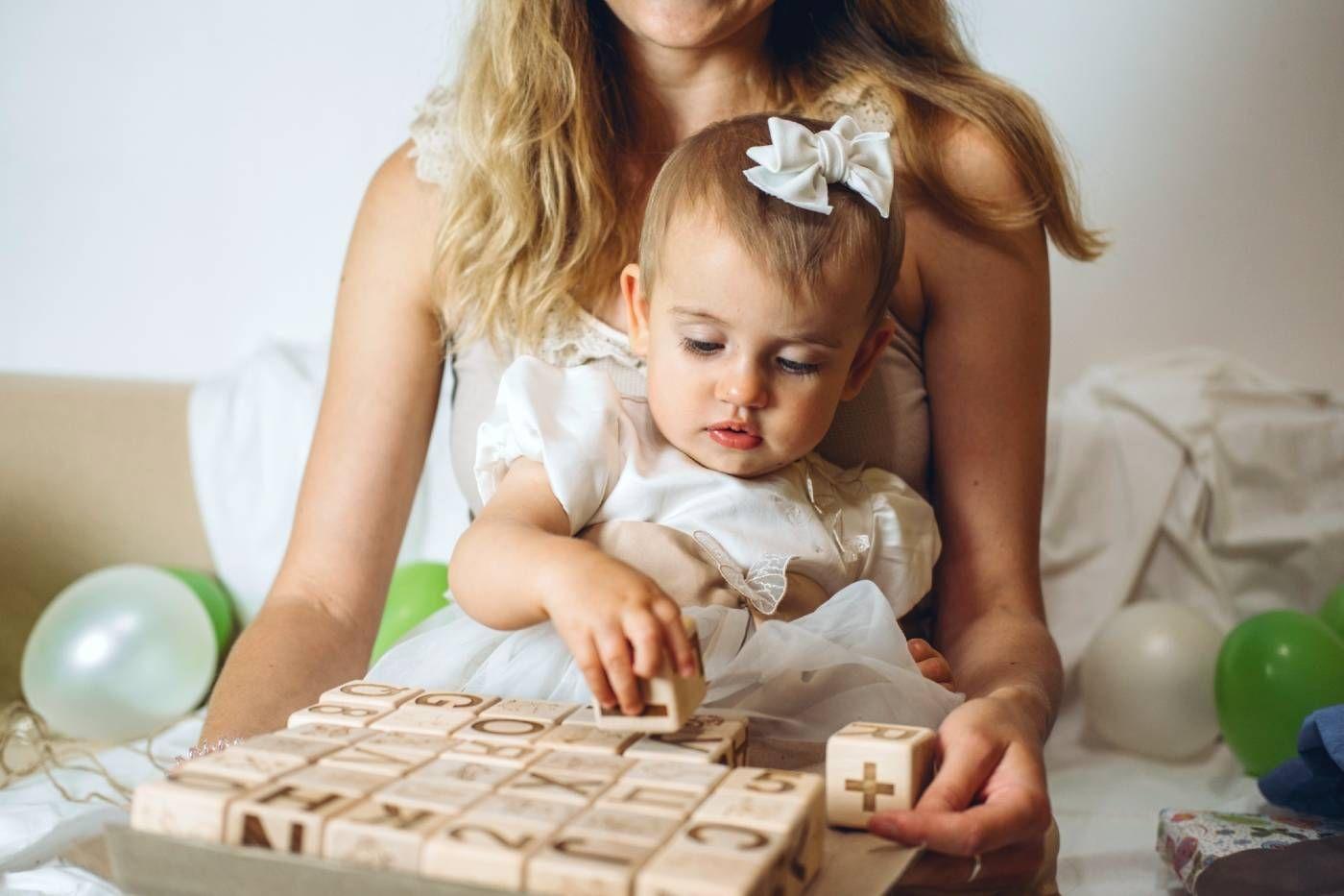 A toddler girl plays with wooden blocks