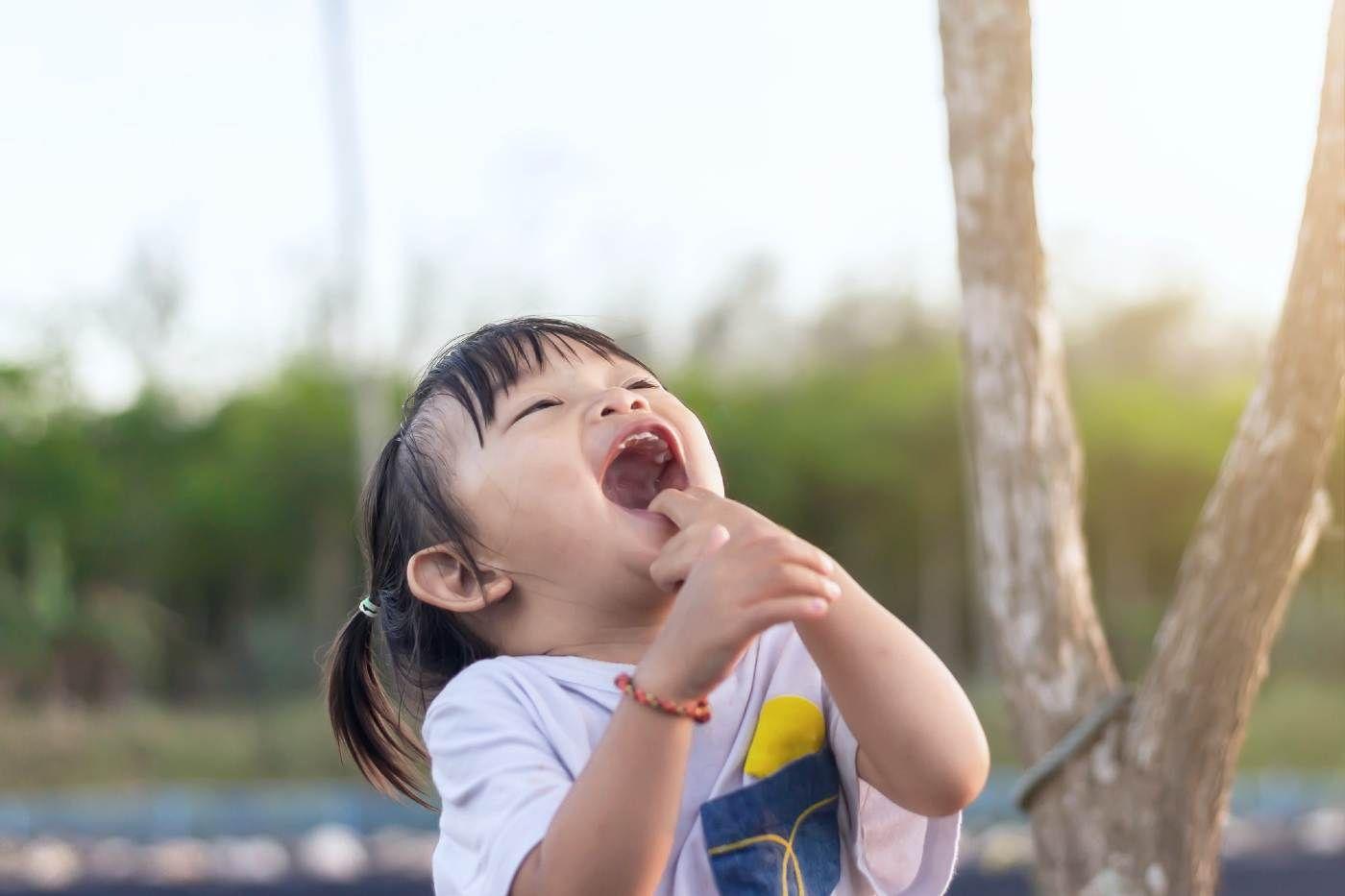 toddler jokes - toddler girl throwing her head back and laughing
