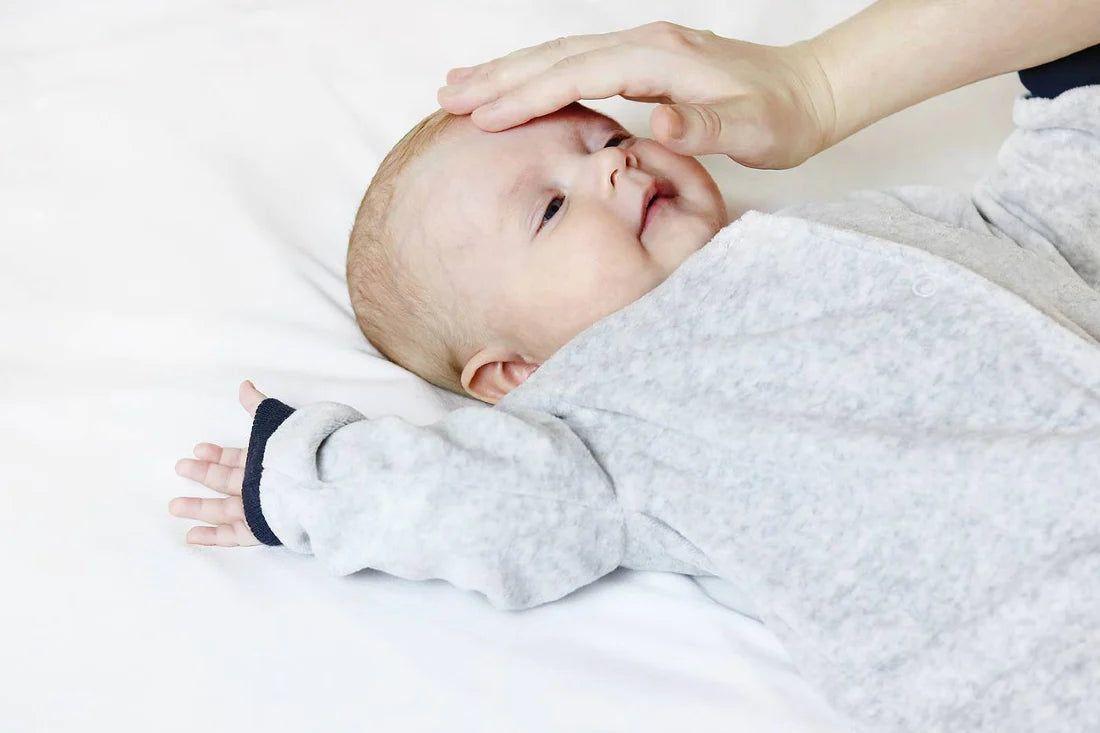 Mum touching baby's forehead to check if baby is overheating