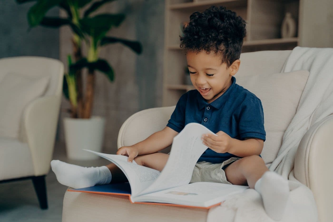 A 3-year-old boy happily reads a book